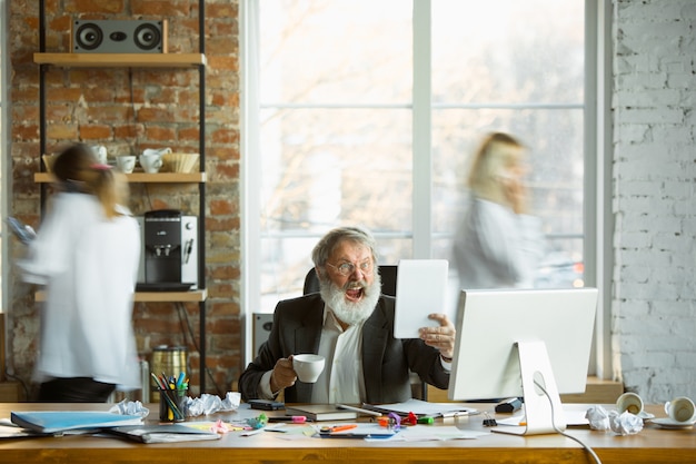 Free Photo nervous and tired boss at his workplace busy while people moving near blurred. office worker, manager working, has problems and deadline, his colleagues distracting. business, work, workload concept.