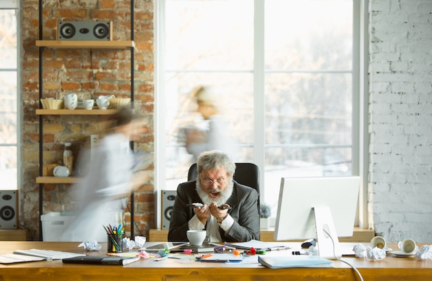 Free Photo nervous and tired boss at his workplace busy while people moving near blurred. office worker, manager working, has problems and deadline, his colleagues distracting. business, work, workload concept.