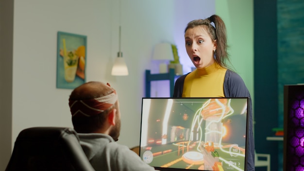 Free Photo nervous woman screaming at husband while he is playing space shooter videogame on rgb powerful computer and streaming online competition. pro cyber with headset performing during virtual tournament