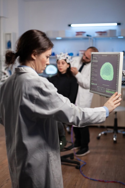 Free photo neurologist specialist analyzing nervous system tomography on monitor while specialist doctor adjusting eeg scanner of woman patient during medical experiment. neurology team monitoring brain activity