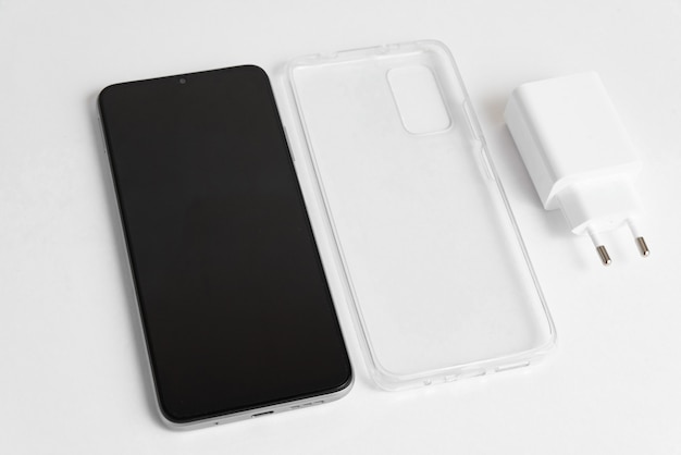 New cellphone and charger with transparent cover over isolated white background