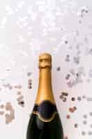 Free photo new champagne bottle and silver round confetti on white background