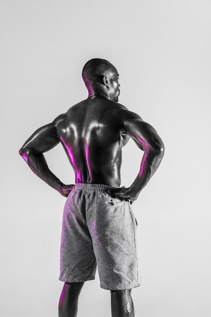 New chance's coming. Studio shot of young african-american bodybuilder training on grey background. Muscular single male model standing in sportwear. Concept of sport, bodybuilding, healthy lifestyle.