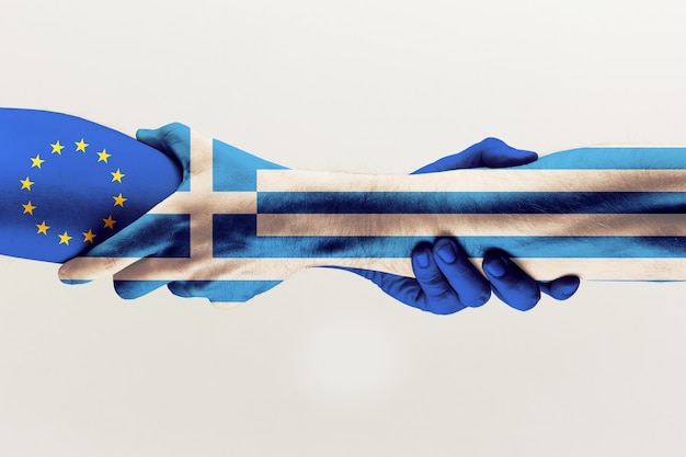 Free photo new chances. male hands holding colored in blue eu and greece flag isolated on gray studio background. concept of help, commonwealth, partnership of countries, political and economical relations.