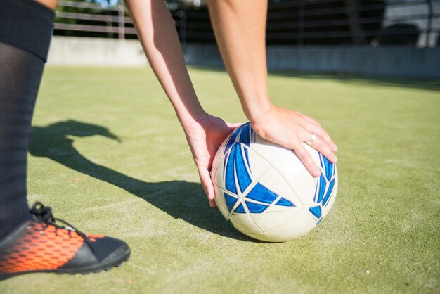 New football ball on sport field. Blue and white soccer ball on sport field. Womans hands putting it on grass. Football, sport,  leisure activities concept