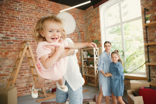 Free Photo new life. adult family moved to a new house or apartment. spouses and children look happy and confident. moving, relations, new life concept. unpacking boxes with their things, playing together.