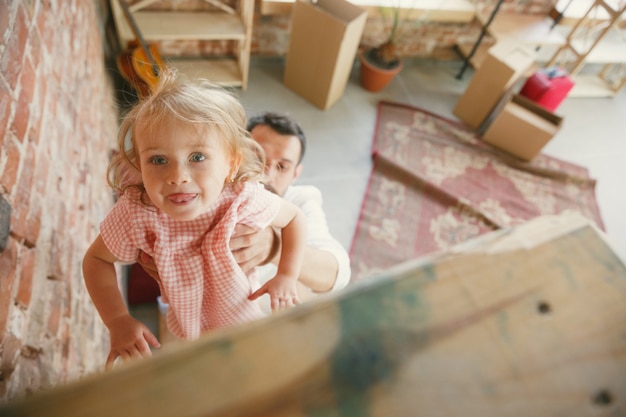 Free Photo new life. young father and his daughter moved to a new house or apartment. look happy and confident