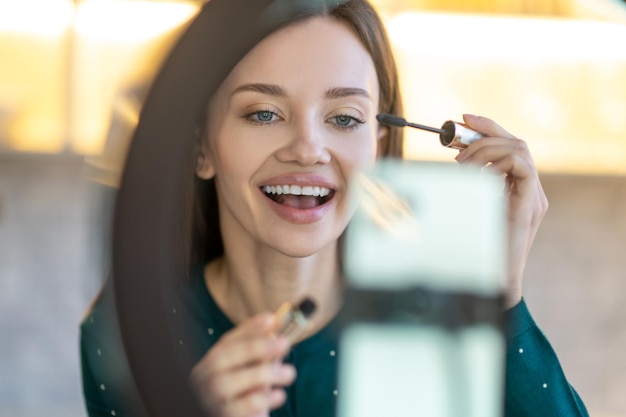 Free photo new mascara presentation. young beautiful woman demonstrating new mascara and looking amused