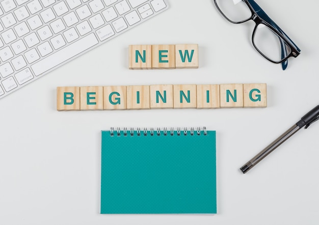 New start and business concept with wooden blocks, glasses, keyboard, pen, notebook on white background flat lay.