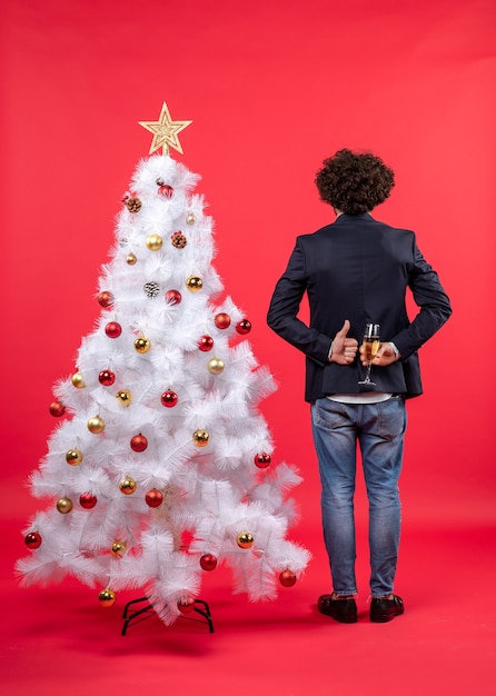 New year celebration with young man holding a glass of wine behind and making ok gesture