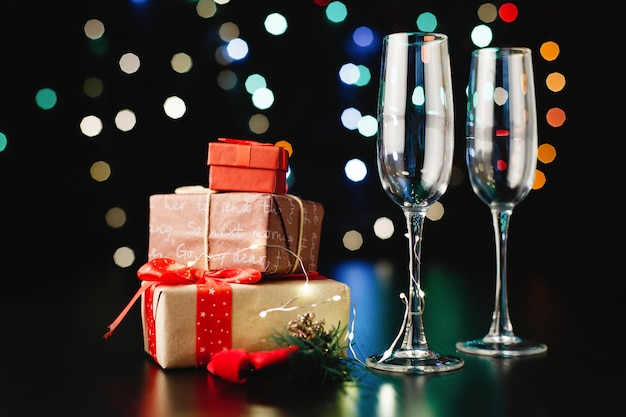 New Year and Christmas decor. Champagne flutes, little presents and green branches 