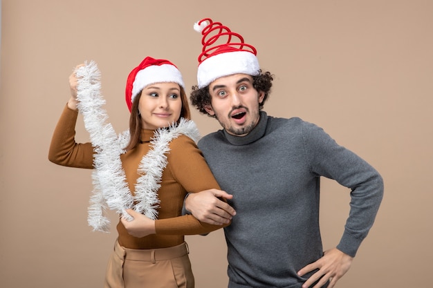 Free photo new year mood festive concept with excited cool satisfied lovely couple wearing red santa claus hats