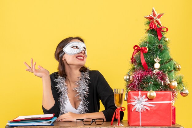 Free photo new year mood with dreamy charming lady in suit wearing mask in the office