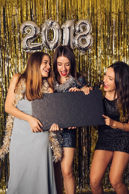 New year party concept with three girls pointing at board