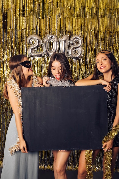 New year party concept with three girls showing chalkboard