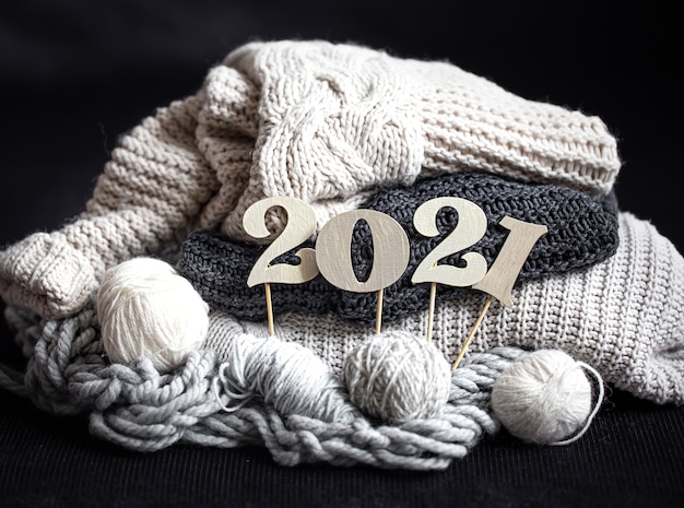 New year's composition with knitted items and wooden new years number on a dark background close up.