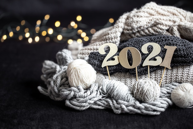 New year's composition with knitted items and wooden new years number on a dark background.