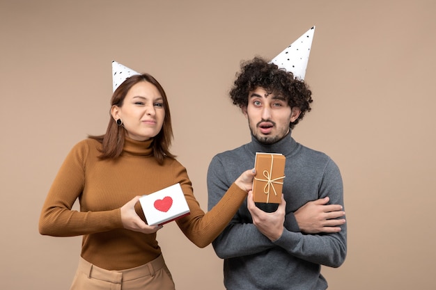 New year shooting with young couple wear new year hat sour face girl with heart and confused guy with gift