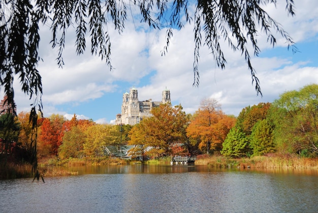 New York City Central Park in Autumn with Manhattan skyscrapers and colorful trees over lake with reflection.