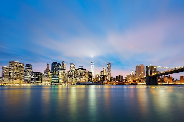 New York City Manhattan midtown at dusk with skyscrapers illuminated over east river