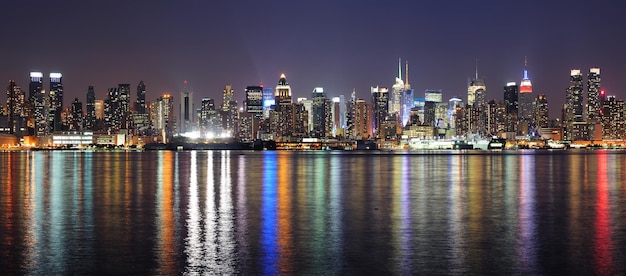 New York City Manhattan midtown skyline at night with lights reflection over Hudson River viewed from New Jersey Weehawken waterfront.