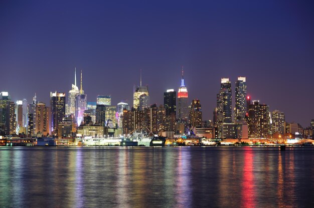 New York City Manhattan midtown skyline at night with lights reflection over Hudson River viewed from New Jersey Weehawken waterfront.