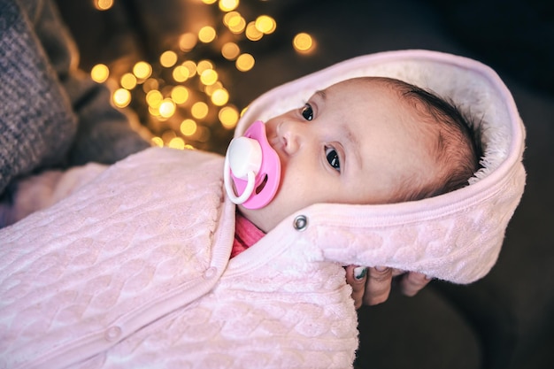 Free photo newborn baby girl with pacifier on blurred background with bokeh