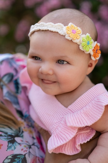 Free photo newborn baby girl with pink knitted clothes and a head accessory among flowers