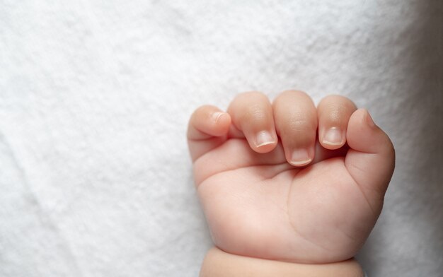 Newborn baby hand in white bed