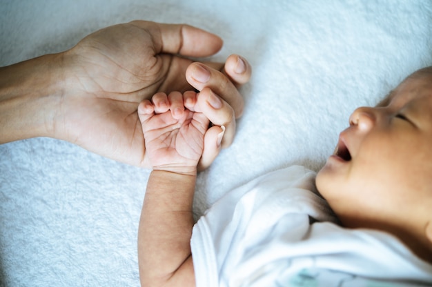 Free Photo newborn baby sleeping and puts the hand on the mother's hand