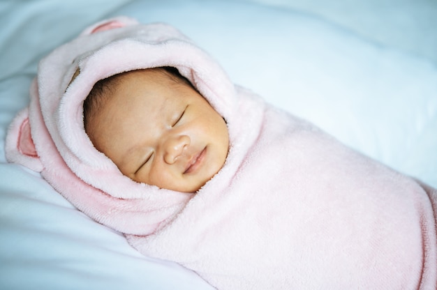 Newborn baby sleeping on a soft pink blanket