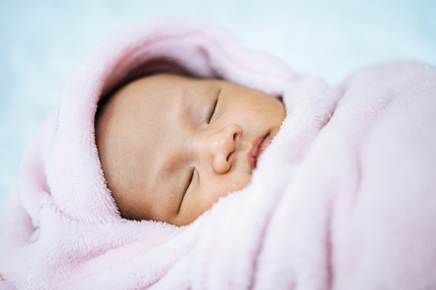 Newborn baby sleeping on a soft pink blanket