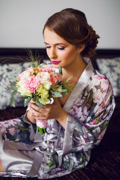 Newlywed beautiful woman start preparation of wedding day in floral bathrobe