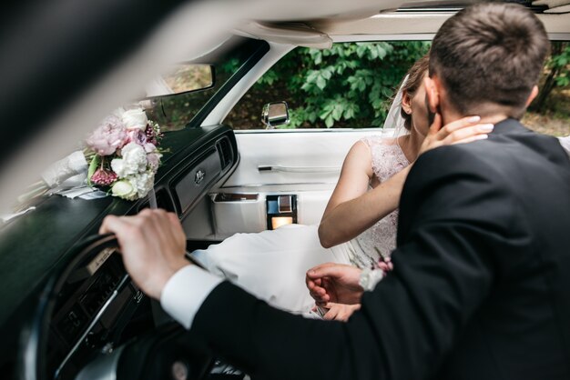 Newlyweds kiss inside a retro Cadillac