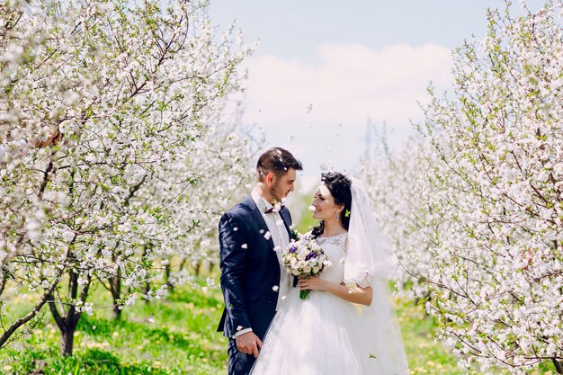 Newlyweds looking at each other with flowers falling from the sky