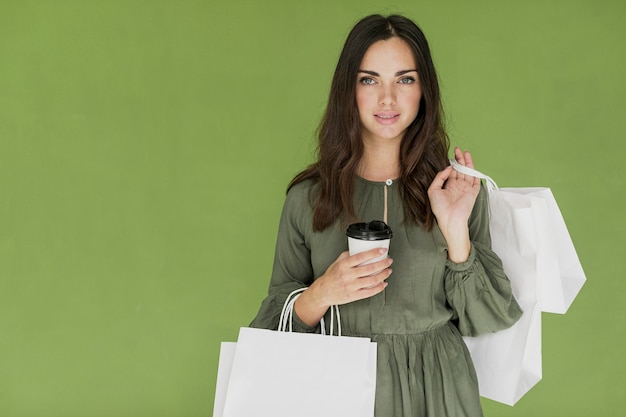 Free Photo nice girl with coffee and many shopping nets on green background