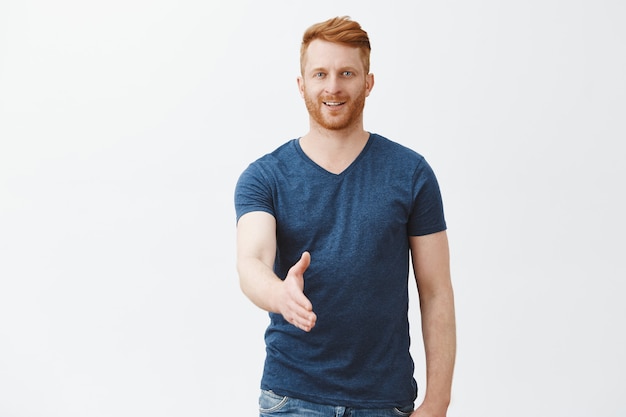 Free Photo nice to meet you. charming and friendly good-looking european ginger man with bristle, pulling hand towards in handshake pose