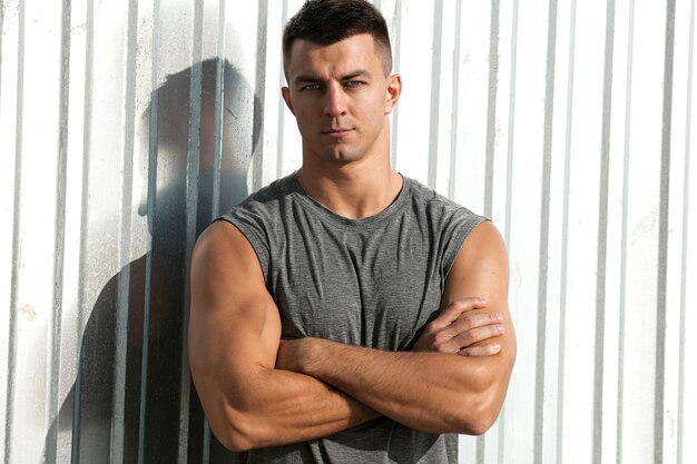 Nice musculature man. Portrait of fitness athlete handsome man posing outdoor with crossed arms