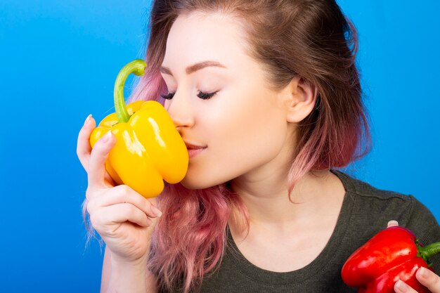 Nice woman smelling a fresh yellow pepper in her hand