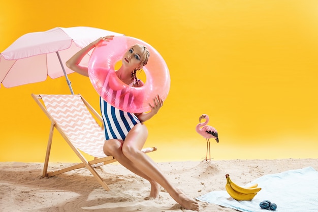 Nice young woman in beach outfit holds pink swimming ring