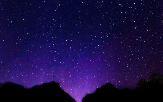 Free Photo night sky with lot of shiny stars with blurred mountain background.