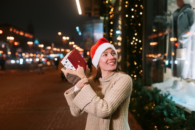 Night street portrait of young beautiful woman acting thrilled. Festive garland lights.