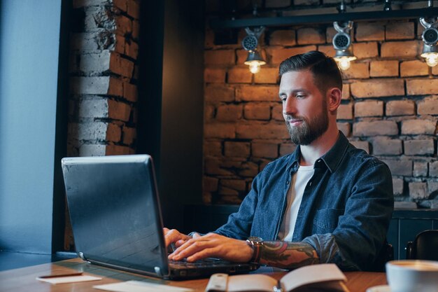 No minute without my laptop. Handsome young man working on laptop while enjoying coffee in cafe.