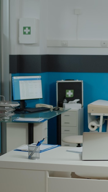 Free photo nobody in doctors office with modern funiture at medical facility. empty examination cabinet for healthcare specialist. close up of white desk with laptop, stethoscope and pens