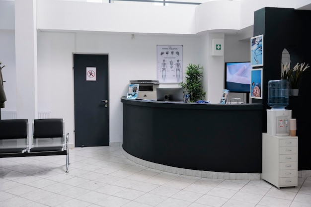 Nobody in waiting room with front desk reception and wall screen tv with promotional offer in private practice hopital. Waiting area for patients with doctor appointments in modern healthcare clinic.