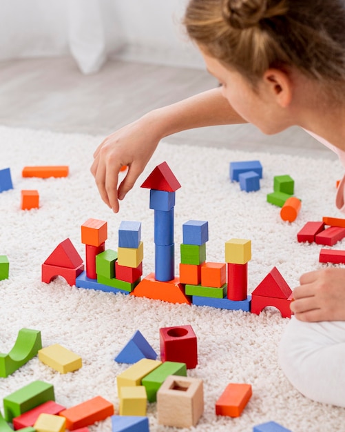 Free Photo non binary kid playing with a colorful game at home