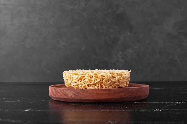 Noodle cube in a wooden plate on black surface