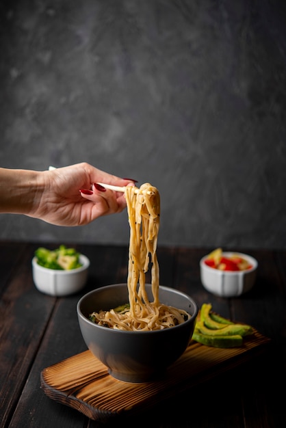 Free photo noodles in bowl with avocado and copy space