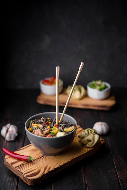 Noodles in bowl with chopsticks and garlic