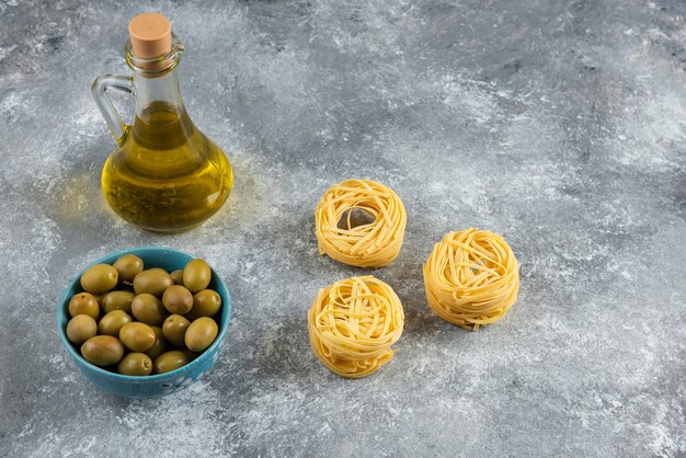 Noodles, oil and green olives on stone.